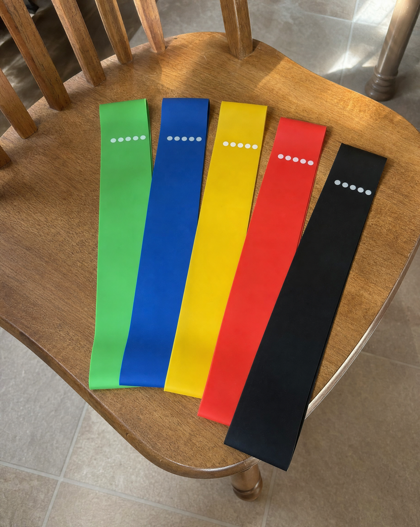 All five loop bands laid out across the seat of a wooden kitchen chair